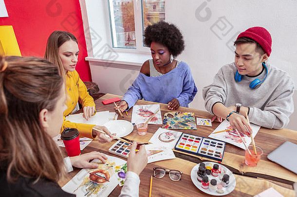 四名艺术系学生坐在桌子旁一起画画