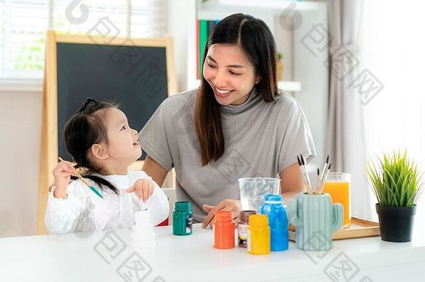 亚洲幼儿园女学生和母亲在家里客厅里用丙烯酸水彩画石膏娃娃。家庭教育与远程学习