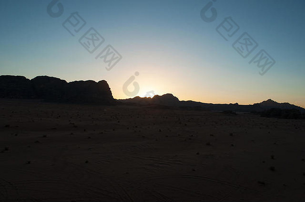 在瓦迪拉姆沙漠（Wadi Rum desert）的一座山的黑暗轮廓上，火红的日落，这是一个著名的月球山谷，看起来像火星