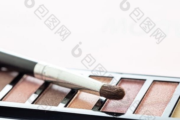 眼影托盘设置柔和的颜色和粉红色背景下的画笔，特写视图。专业化妆工具、美容院、化妆品概念