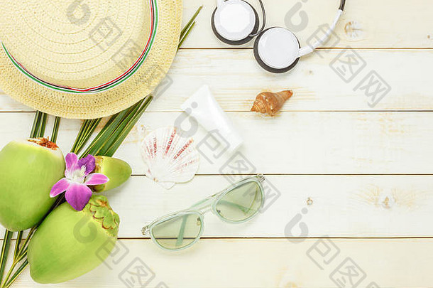 顶视夏日必备旅游用品。防晒耳机椰子帽太阳镜，白色木质背景。