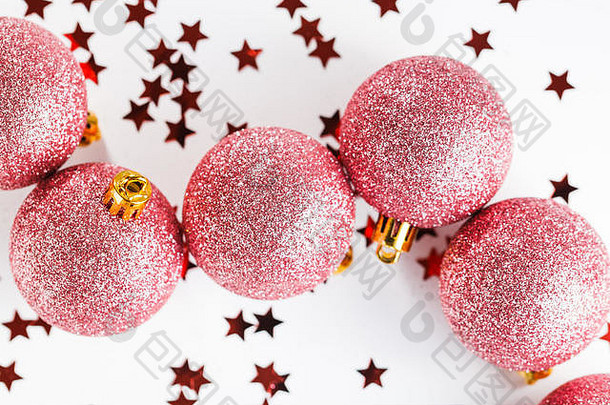 闪烁的圣诞球装饰粉色，白色背景上有星星五彩纸屑。俯视图，平面布置。