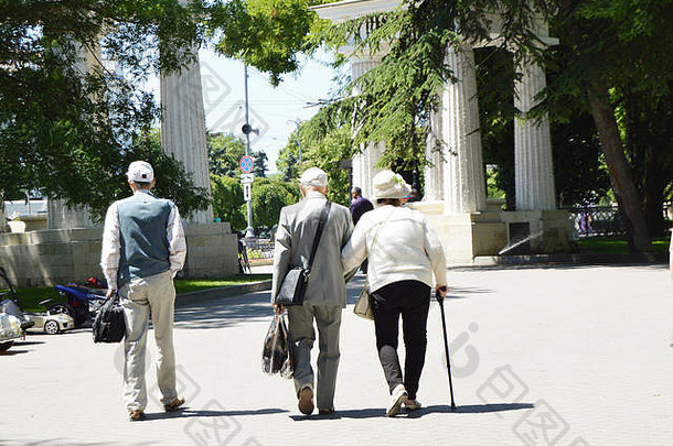 退休老人在公园散步时与朋友的快乐老年夫妇的后视图