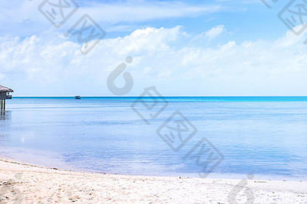 在蔚蓝的天空下，在海边美丽的沙滩上坐着椅子。暑期休闲的概念是一种旅游度假的理念。空拷贝空间