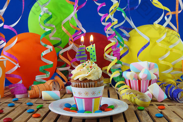 <strong>41</strong>生日纸杯蛋糕，蜡烛在乡村木桌上燃烧，背景是五颜六色的气球，背景是<strong>蓝色</strong>墙上的塑料杯糖果
