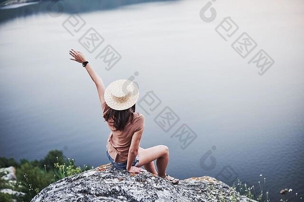 感受自由。美丽的旅游女孩在山脚下摆好姿势，背景是清澈的湖水
