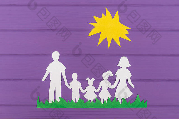 在紫色木质<strong>背景</strong>上，男人和女人以及两个女孩和男孩在阳光下的草地上剪纸的剪影。家庭统一的概念