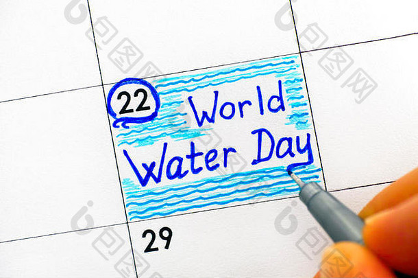 女人用手指在日历上用钢笔写下<strong>世界水日</strong>的提示。3月22日。特写。