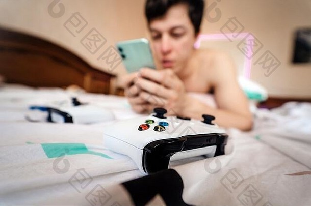 一个人躺在床上，在室内使用智能手机的特写镜头。