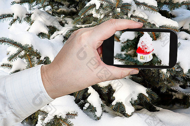 旅游理念-游客在户外的圣诞树上用手机拍摄新的白色玻璃房子