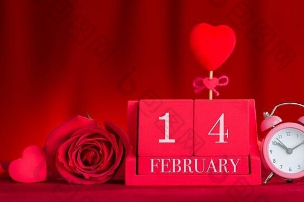 2月14日红色木制立方体日历上的字母。红色面料背景前的情人节概念。