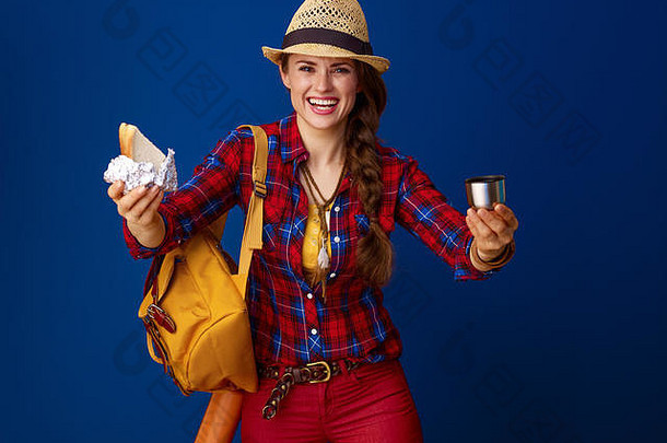搜索鼓舞人心的的地方快乐年轻的旅游女人格子衬衫给三明治热饮料孤立的蓝色的背景