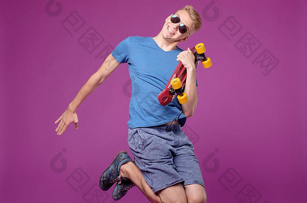 男子手拿滑板在紫色背景上跳跃，便士小板，动作