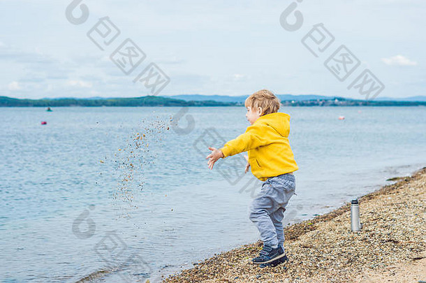 小男孩在海水中扔石头。