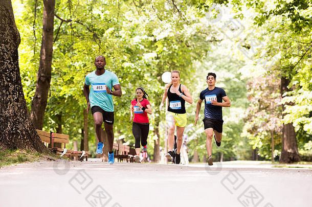 一群年轻运动员在绿色阳光公园跑步。