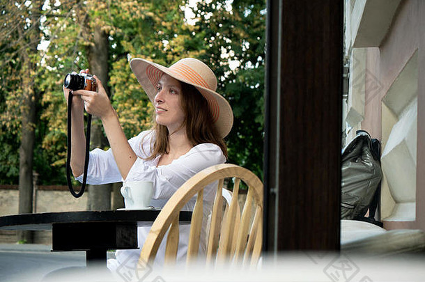 旅游女人古董数字相机拍摄喝咖啡城市街咖啡馆阳台年轻的女孩他白色衬衫持有