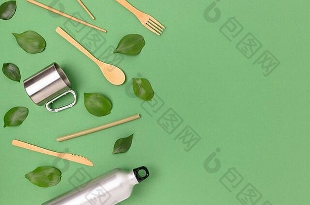绿色粉彩背景上的<strong>竹餐具</strong>套装、金属瓶和马克杯。具有空间的无塑料概念。