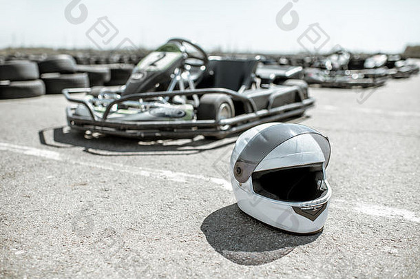 露天跑道上的防护头盔，背景为卡丁车