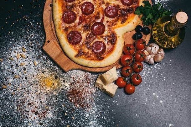 黑底意大利香肠、西红柿、马苏里拉、大蒜和欧芹做成的心形比萨。