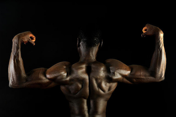 一个黑人，有着肌肉发达的身体和黑色的背景。
