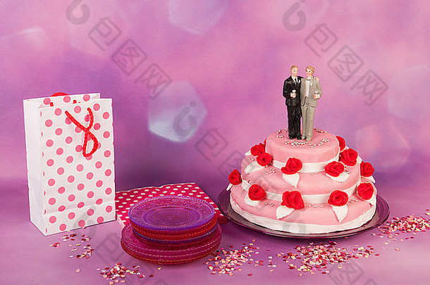 粉色婚礼蛋糕，上面有红玫瑰和夫妇