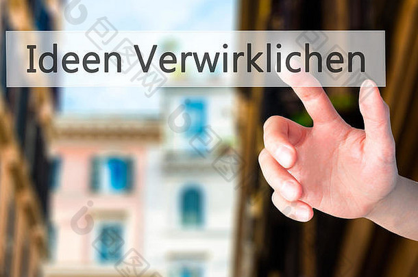Ideen Verwirklichen（用德语实现想法）-手按模糊背景上的按钮。商业、技术、互联网概念。股票