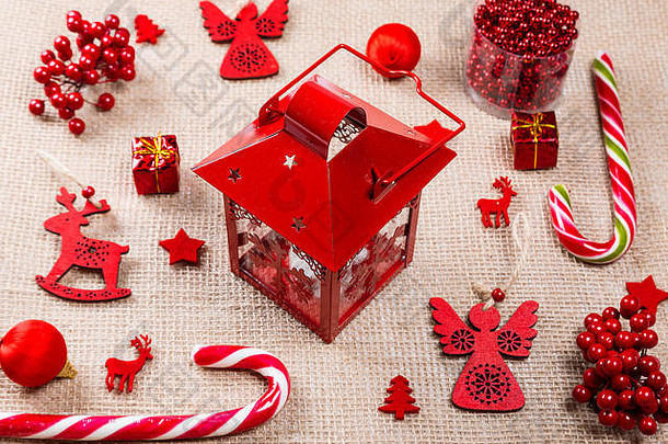 圣诞背景由红色玩具、糖果、礼物、灯笼和粗麻布上的新年装饰品组成。平面布局、俯视图、空间。圣诞快乐卡