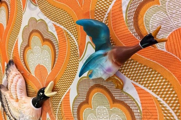 一只70年代复古的壁挂式鸭子在70年代的墙纸上飞来飞去，就像电视连续剧《加冕街》中希尔达·奥格登的房子一样
