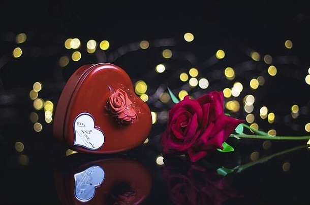 情人节背景。礼品、红玫瑰、五彩纸屑、黑色背景的信封以及心形波基灯。情人节的概念。平铺