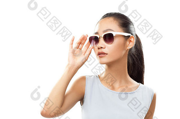 亚洲女孩触摸灰色上衣太阳镜的半身肖像。女模特站直，触摸太阳镜的顶端