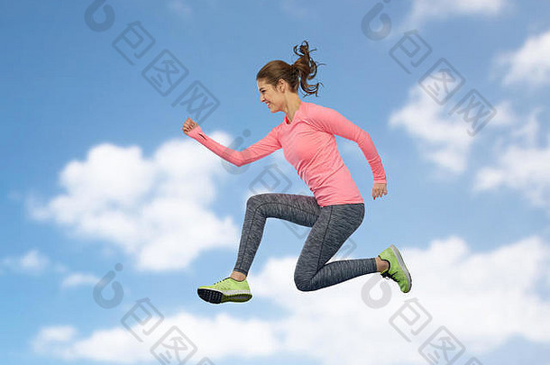 快乐微笑的运动型年轻女子在空中跳跃