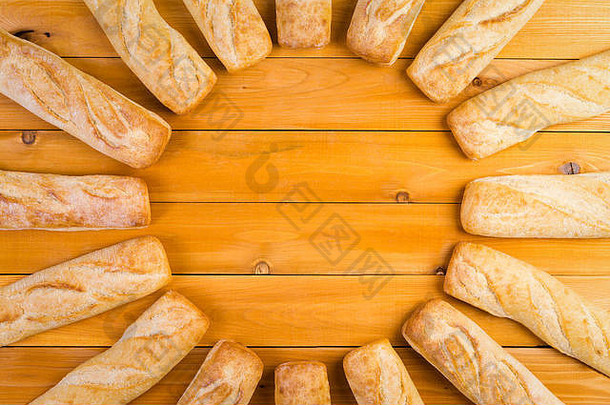 刚烤好的法式硬面包的圆形框架，呈放射状排列在一张<strong>木</strong>桌上，中间有一份副本