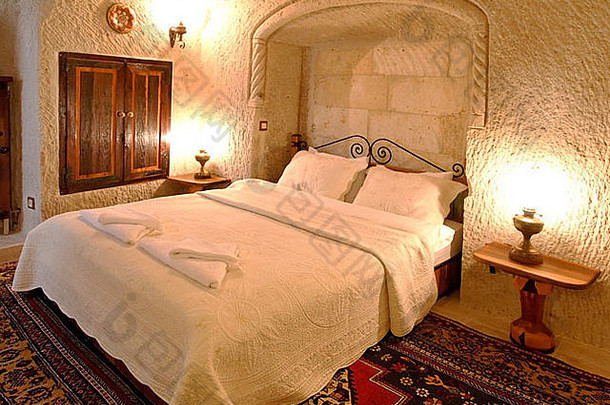 卧室的建筑内部细节，黄铜装饰床头板，白色亚麻布和靠垫，镶嵌壁橱