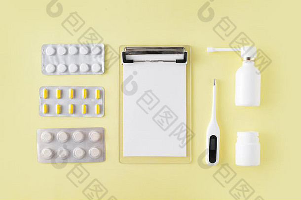 黄色背景上的药丸、温度计和说明。感冒和流感治疗套装。平面布置，俯视图。