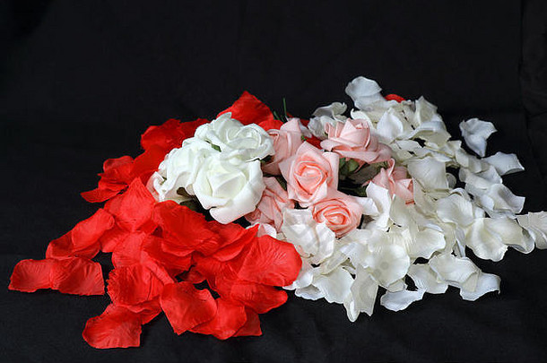 红色和白色的花瓣散落在粉红色和白色的玫瑰花束周围，表示婚礼和爱情的概念