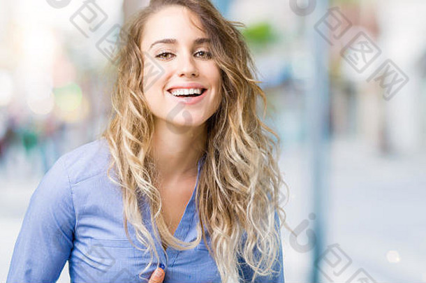 美丽的年轻金发女商人在孤立的背景下微笑着，大声大笑，因为有趣的疯<strong>狂笑</strong>话。高兴的表情。