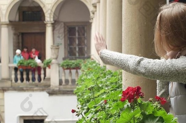 阳台上漂亮的白人女孩在阳台上使用手机。背景是美丽的中世纪圆柱