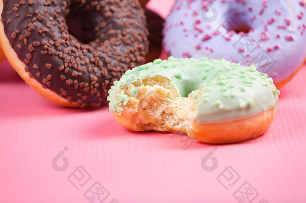 甜甜的五颜六色的美味甜甜圈，糖衣和粉彩粉背景。