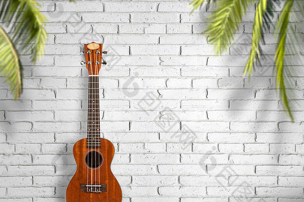 白色墙壁背景上的四弦琴吉他。旅游和生活方式的概念。