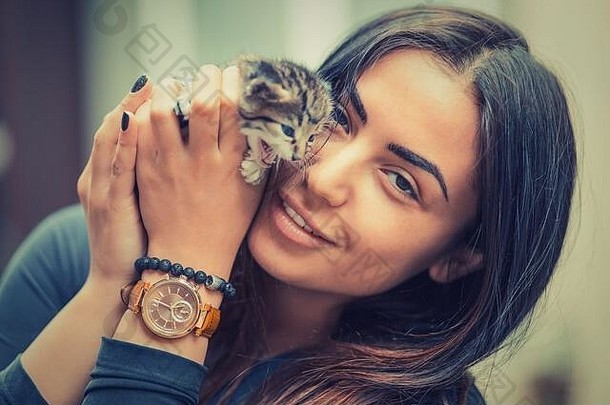 <strong>宠物</strong>护理。年轻女子抱着猫<strong>回家</strong>，微笑着看着你的相机。特写镜头：女人手中的条纹可爱猫。动物之爱。爱猫者。朋友