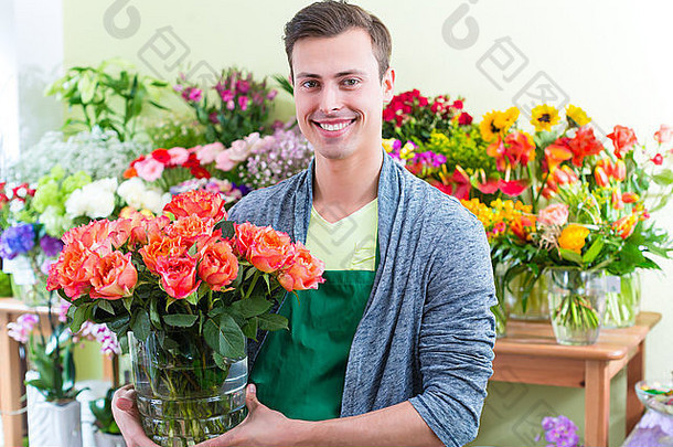 年轻英俊的花商在商店里卖鲜花
