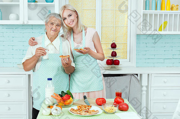 小女孩和她的祖母在厨房里吃比萨饼。