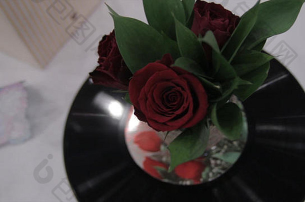 玫瑰和唱片的音乐花束。美丽的红玫瑰花束在克乙烯基上。玫瑰和唱片。酿造的