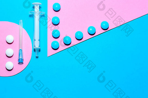 医疗用品和药丸极简平面布置在蓝色和粉色的纸背景上，带有复印空间