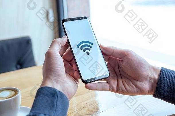 智能手机显示屏上的Wi-fi概念图标。在咖啡馆里手持手机。免费互联网和全球连接的概念