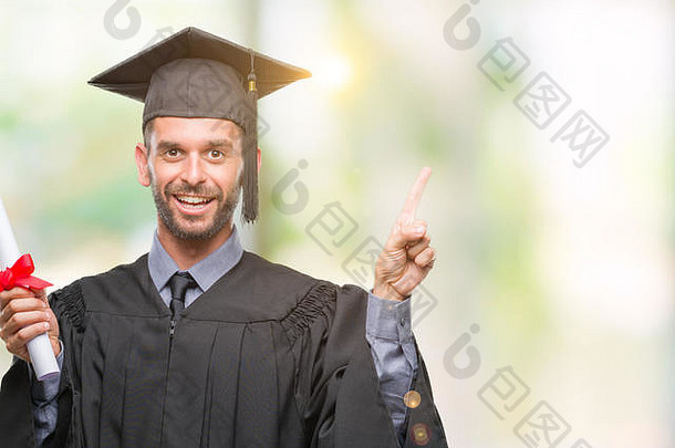 年轻英俊的毕业生，在与世隔绝的背景下拿着学位，非常高兴地用手和手指指着身边