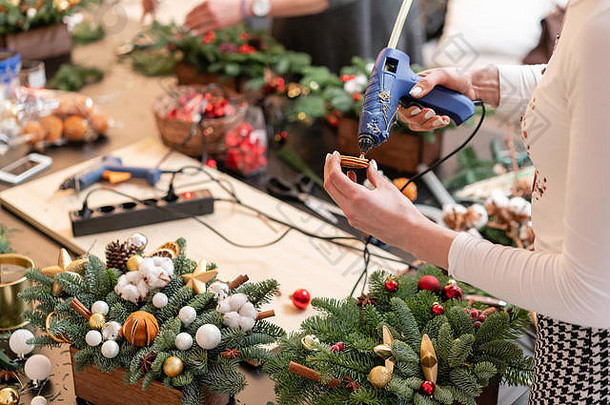 女人手里拿着胶水。圣诞节用松树枝制成的圣诞花环的制造商。制作装饰饰品的<strong>硕士班</strong>。