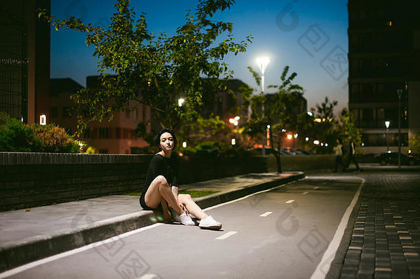 年轻的女人美丽的脚穿着白色运动鞋黑色的衣服背景城市风景街时尚晚上黑暗风格