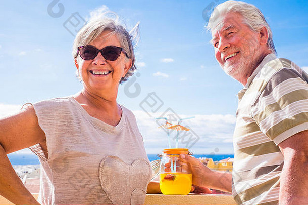 夫妇高级岁的喝水果汁屋顶阳台美丽的海洋视图假期退休概念