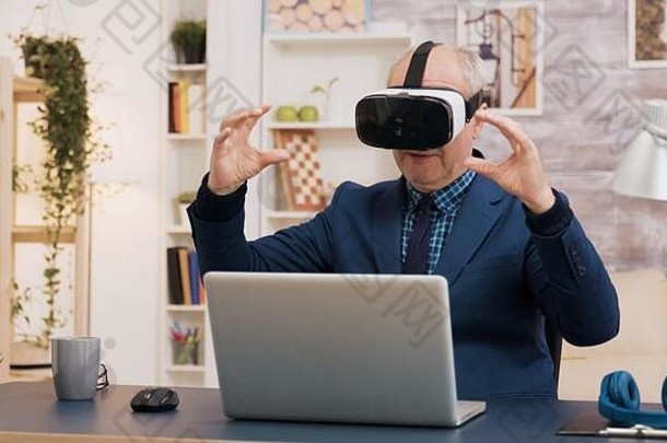 退休男子在客厅使用虚拟现实耳机体验虚拟现实。桌上有一杯咖啡。